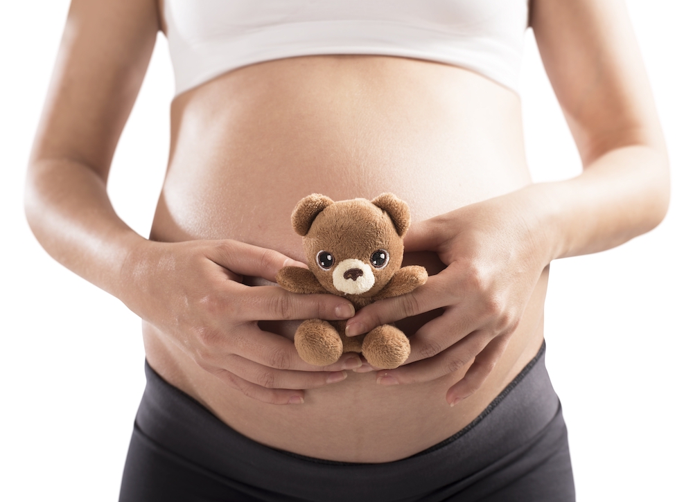 Loving pregnant woman with small teddy bear